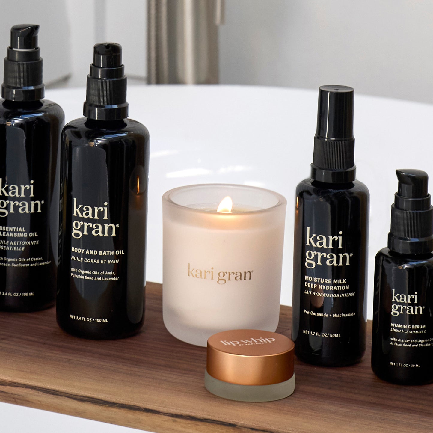 Kari Gran skincare and candle products on a wooden shelf.