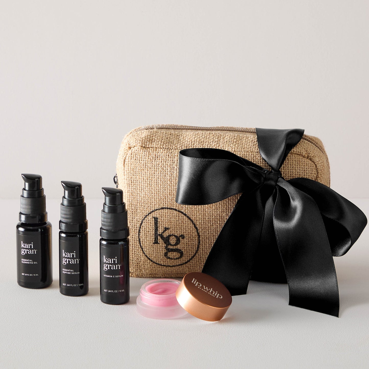 Cleansing oil, peptide serum, vitamin c serum and tinted lip whip next to gift bag