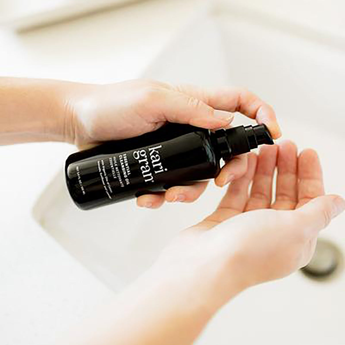 woman putting Kari Gran Cleansing Oil in palm of hand