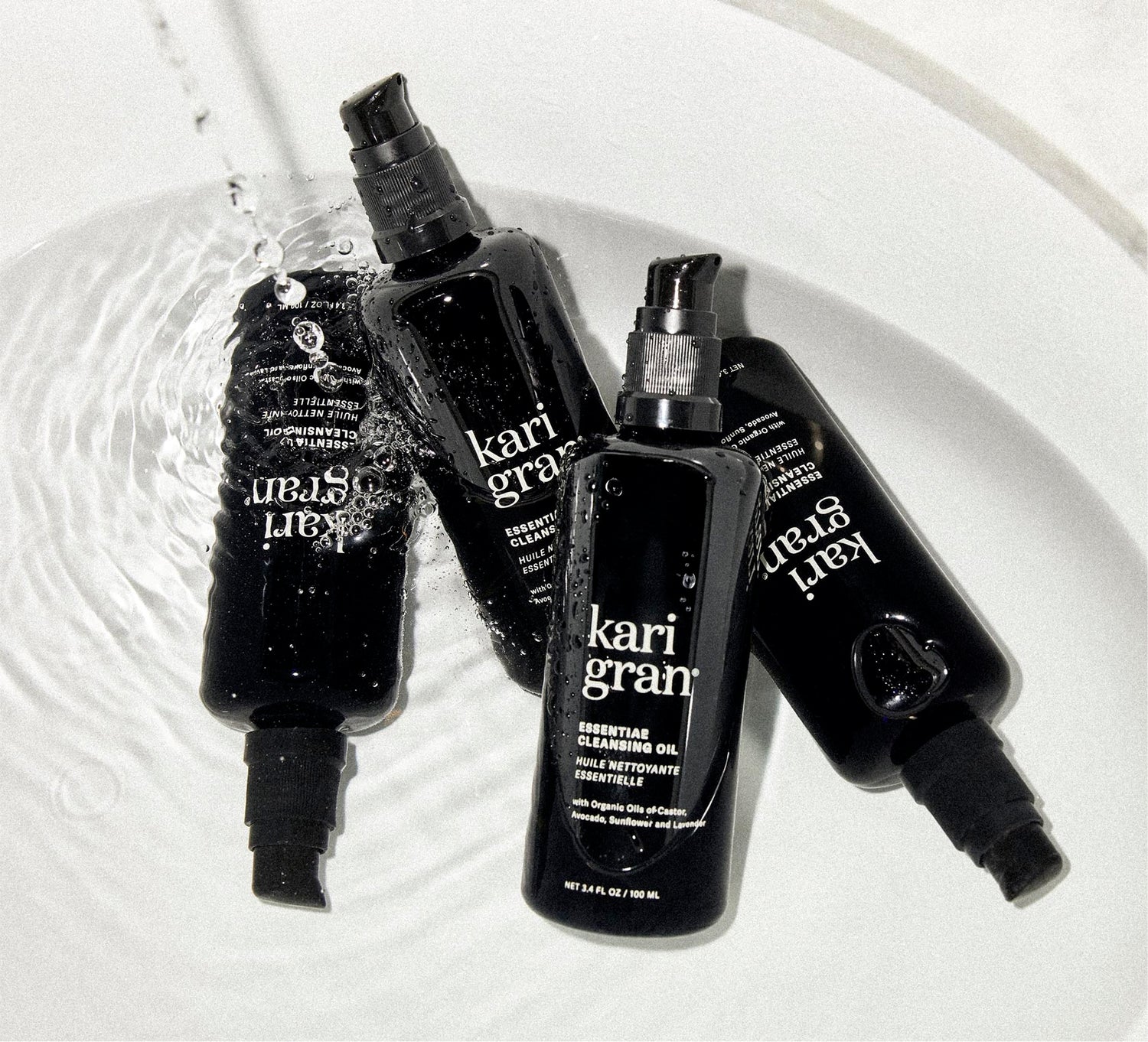 Kari Gran hair care products on a white surface with water droplets.