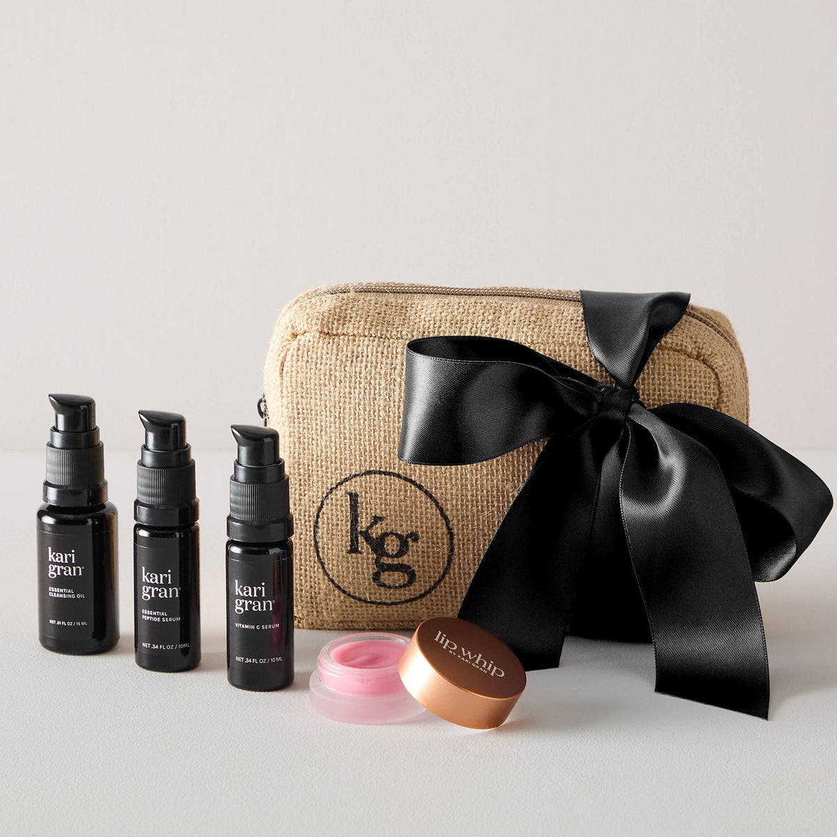 Cleansing oil, peptide serum, vitamin c serum and tinted lip whip next to gift bag